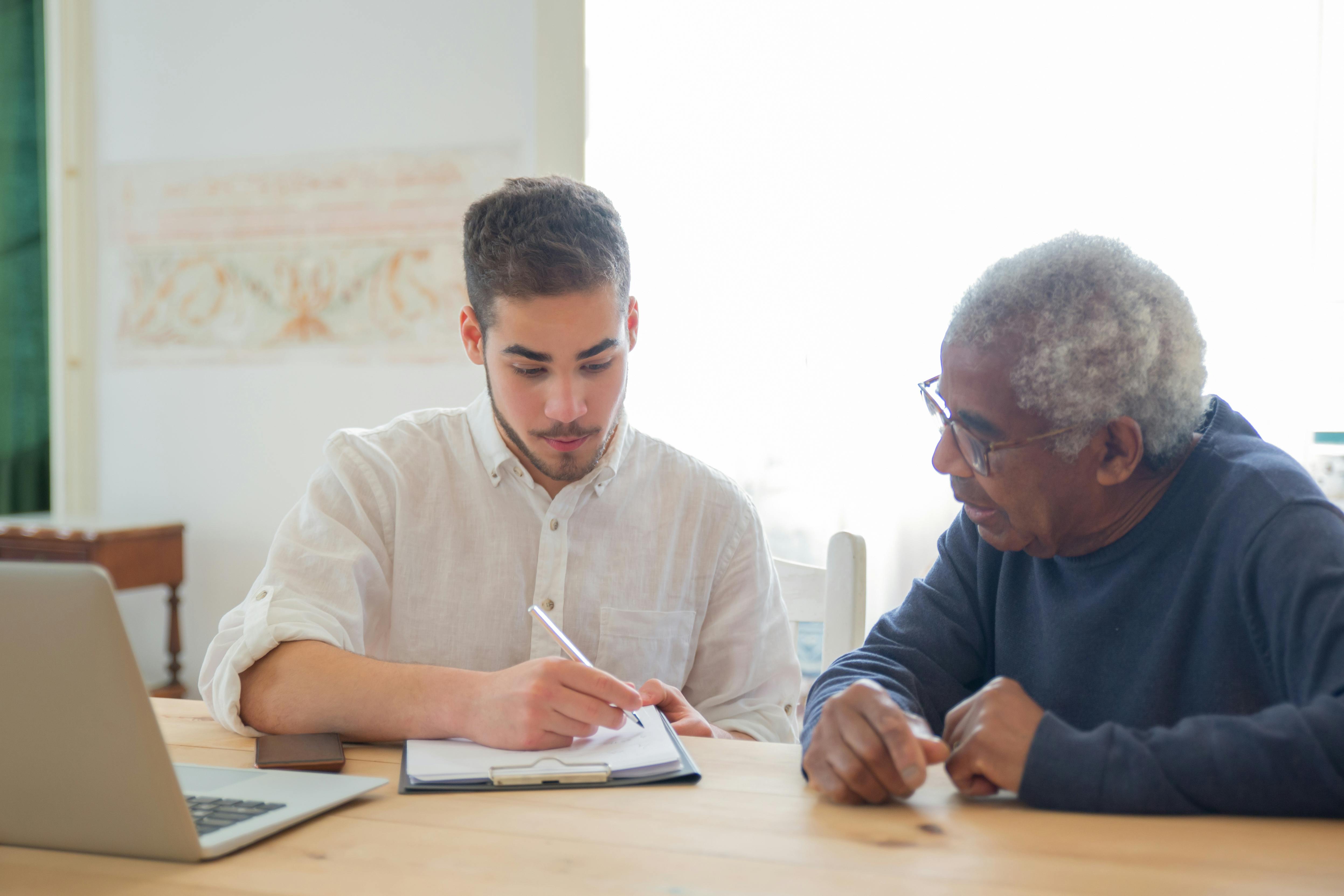 a man in white shirt is sitting beside an elderly man