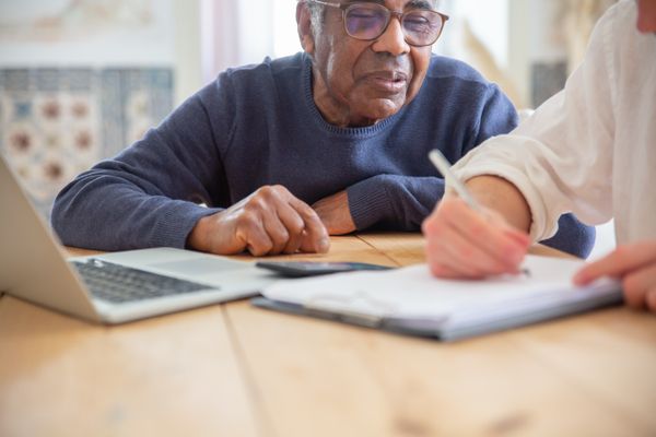 Senior African American man receiving assistance with paperwork at home