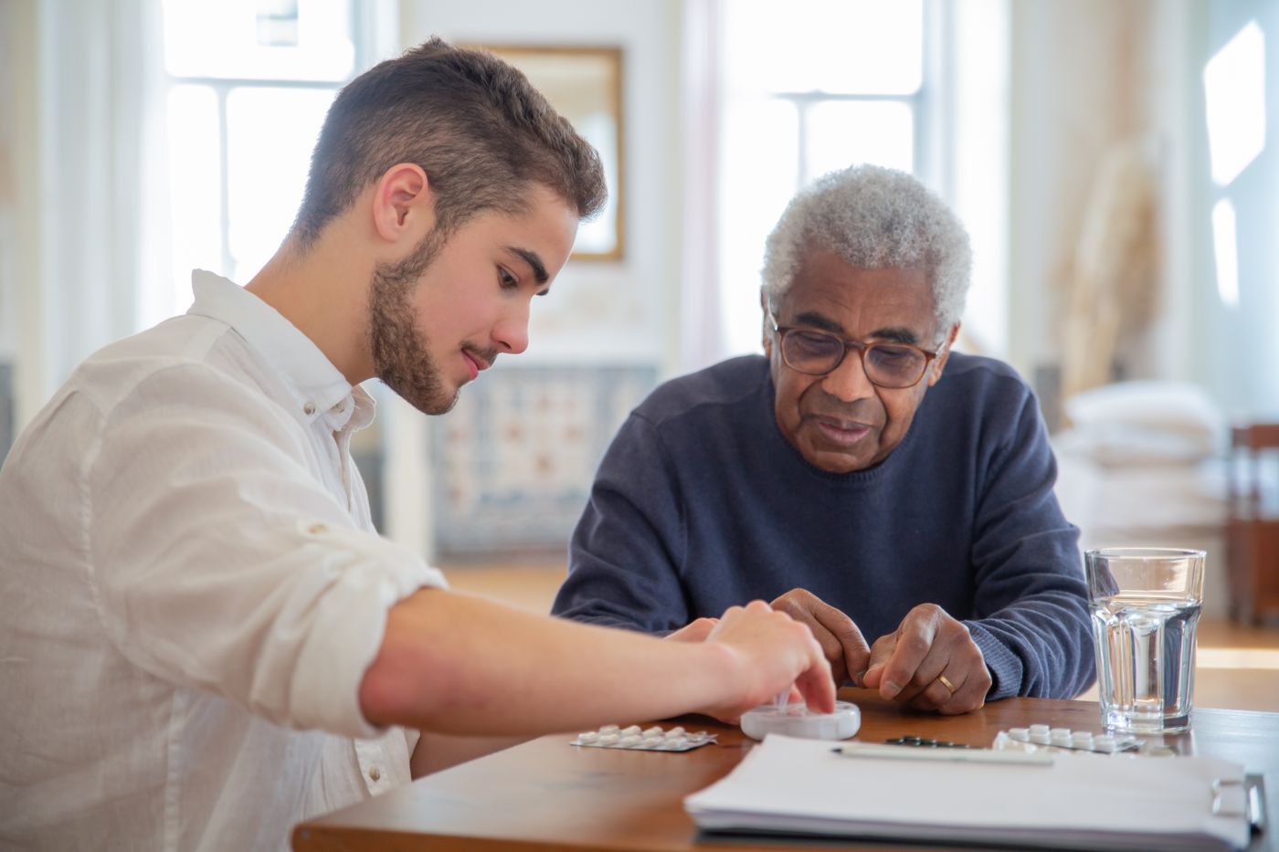 An adult child talks with an older parent at home while reviewing daily care notes