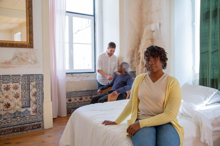 Woman In Yellow Sweater Sitting On Bed 