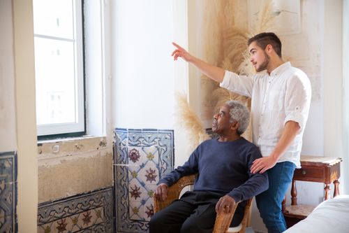 Caregiver engaging with elderly man by window in his home