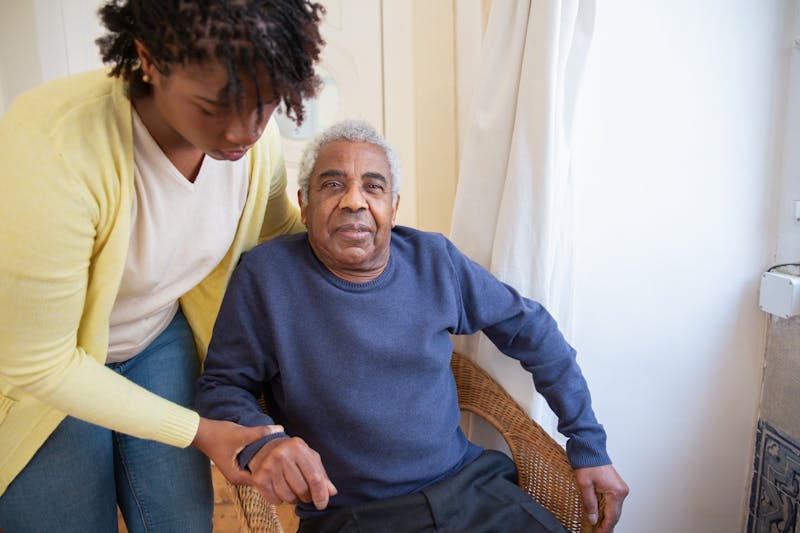 Caregiver providing attentive support to elderly man at home