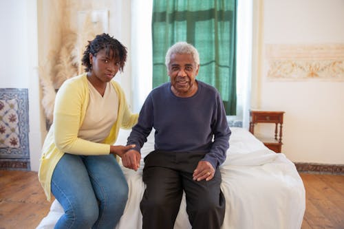 Free Woman and Elderly Man Sitting on Bed Stock Photo