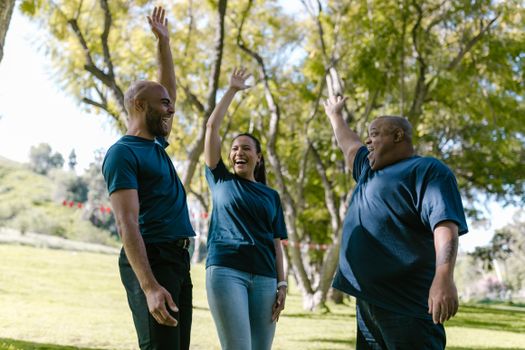 Group of diverse adults engaging in a joyful team building activity outdoors in a park.