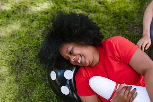 Free Woman in Red Shirt Lying on Green Grass  Stock Photo