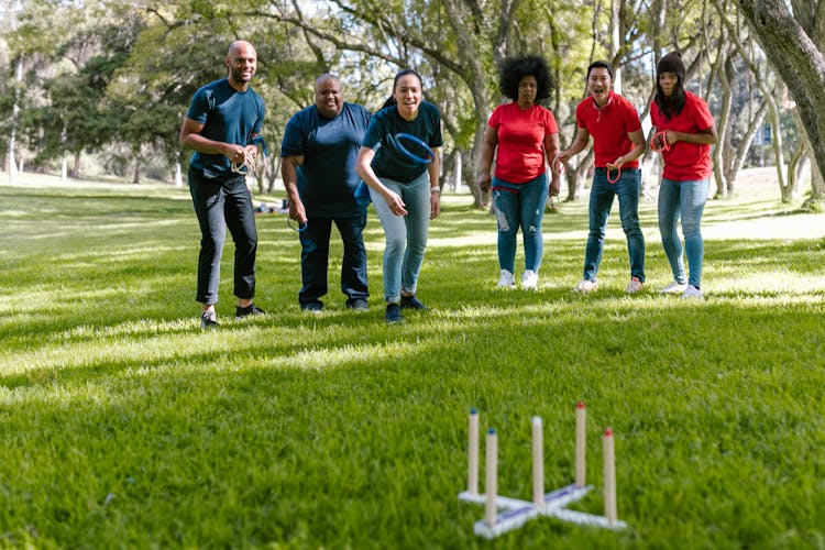 Group Of People Playing On Green Grass Field