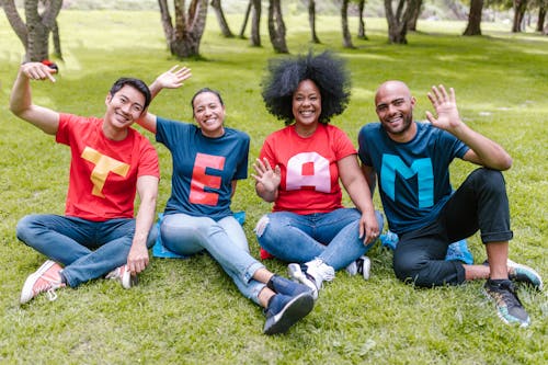 People Sitting on Green Grass Waving Their Hands