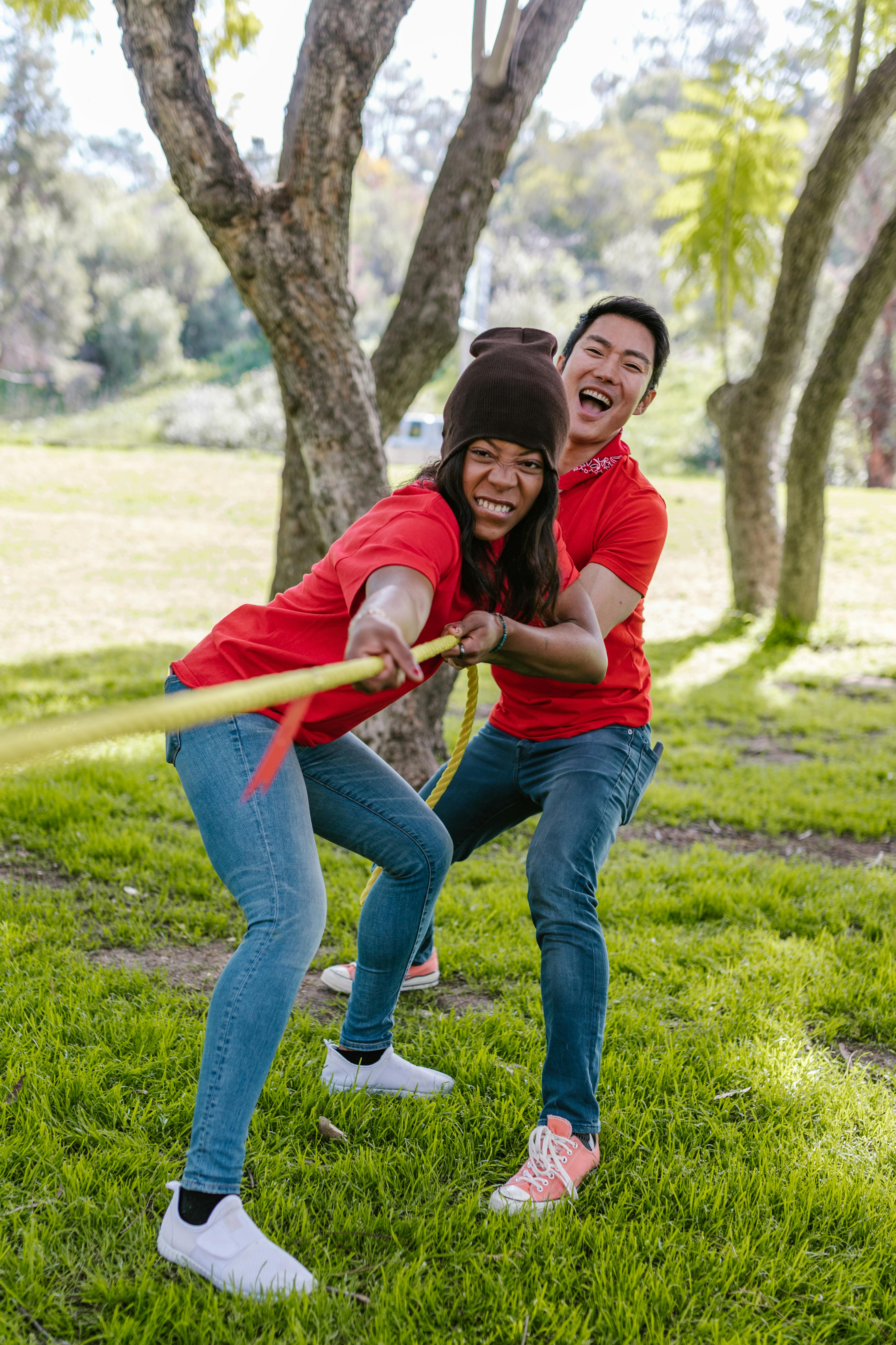 Determined team pulling rope in tug-of-war in park - Stock Image