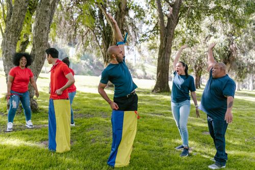 Free Group of adults enjoying team building games with cheer in a green park. Stock Photo