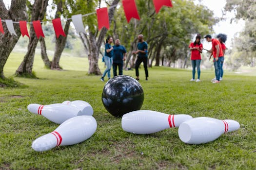 A group of adults playing inflatable bowling for team building outdoors.