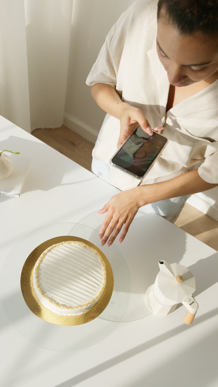 Person Taking Photo Of The White Cake On White Table