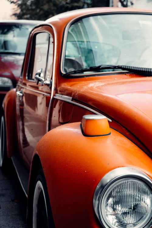 Free Detailed close-up of a classic orange Volkswagen Beetle parked outdoors, showcasing its headlight and distinct curves. Stock Photo
