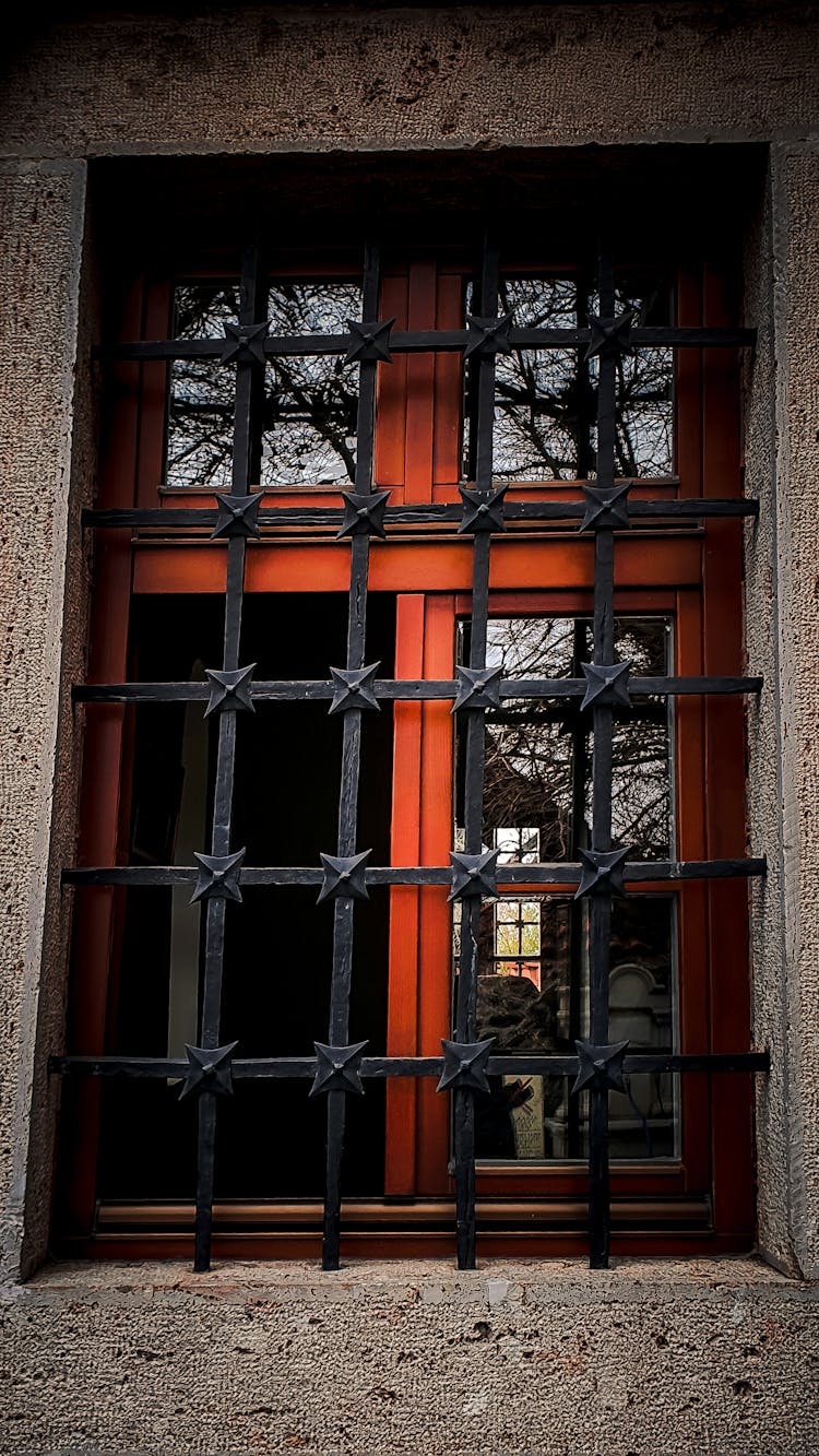 Red Window Frame With Metal Bars In Concrete Wall