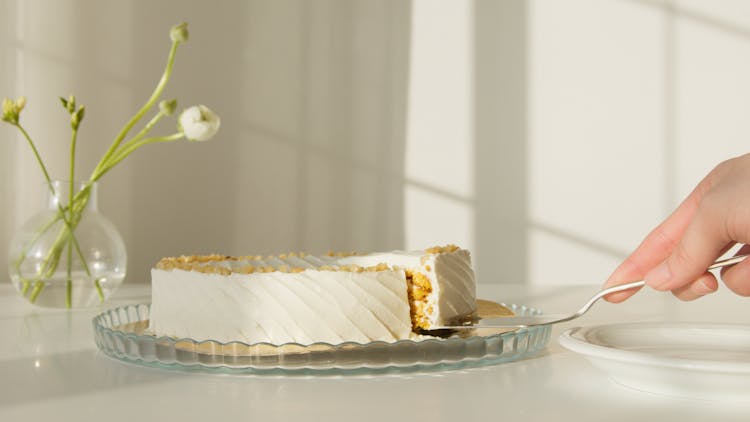 A Person's Hand Getting A Slice Of Cake