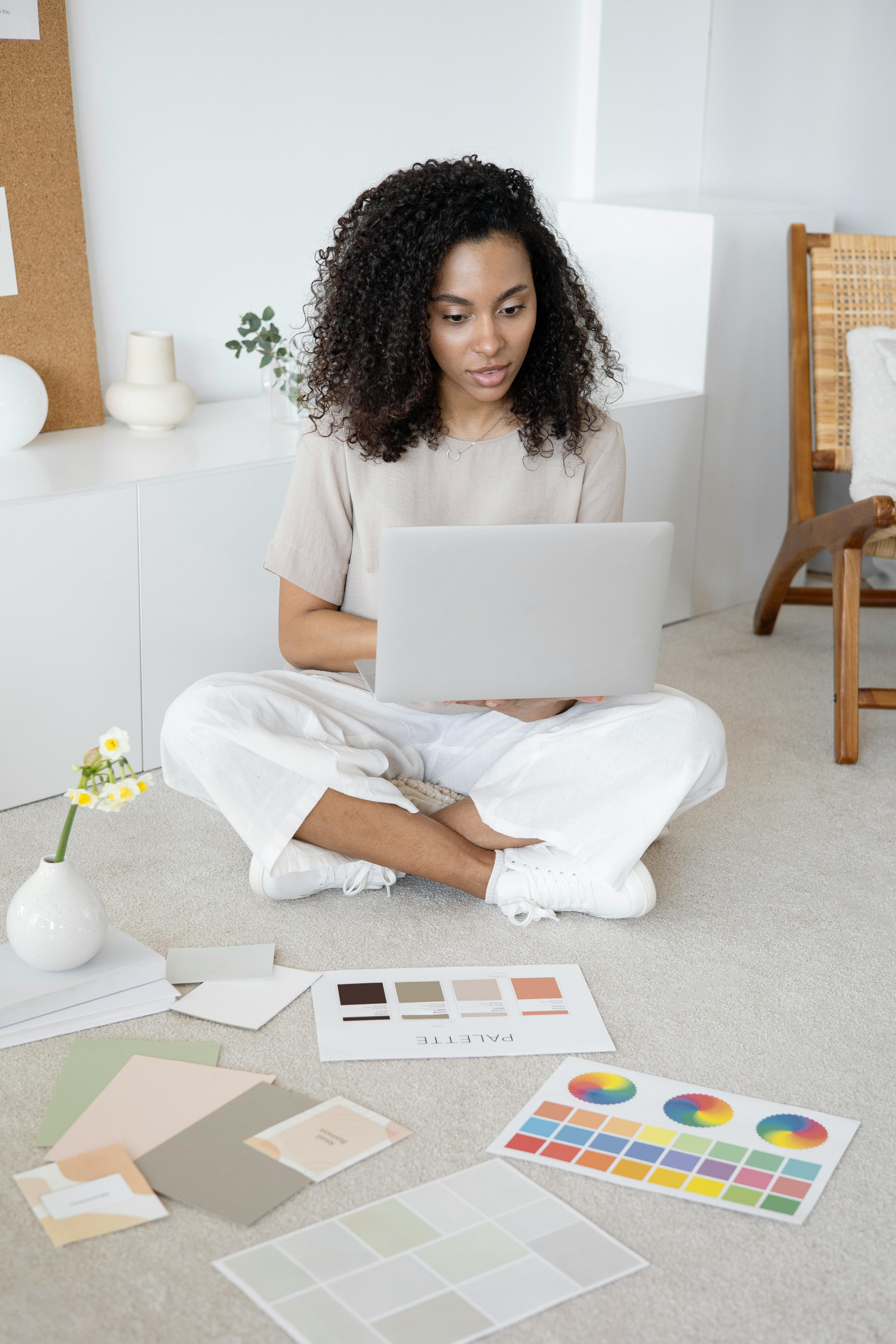 a woman using her laptop while sitting on the floor