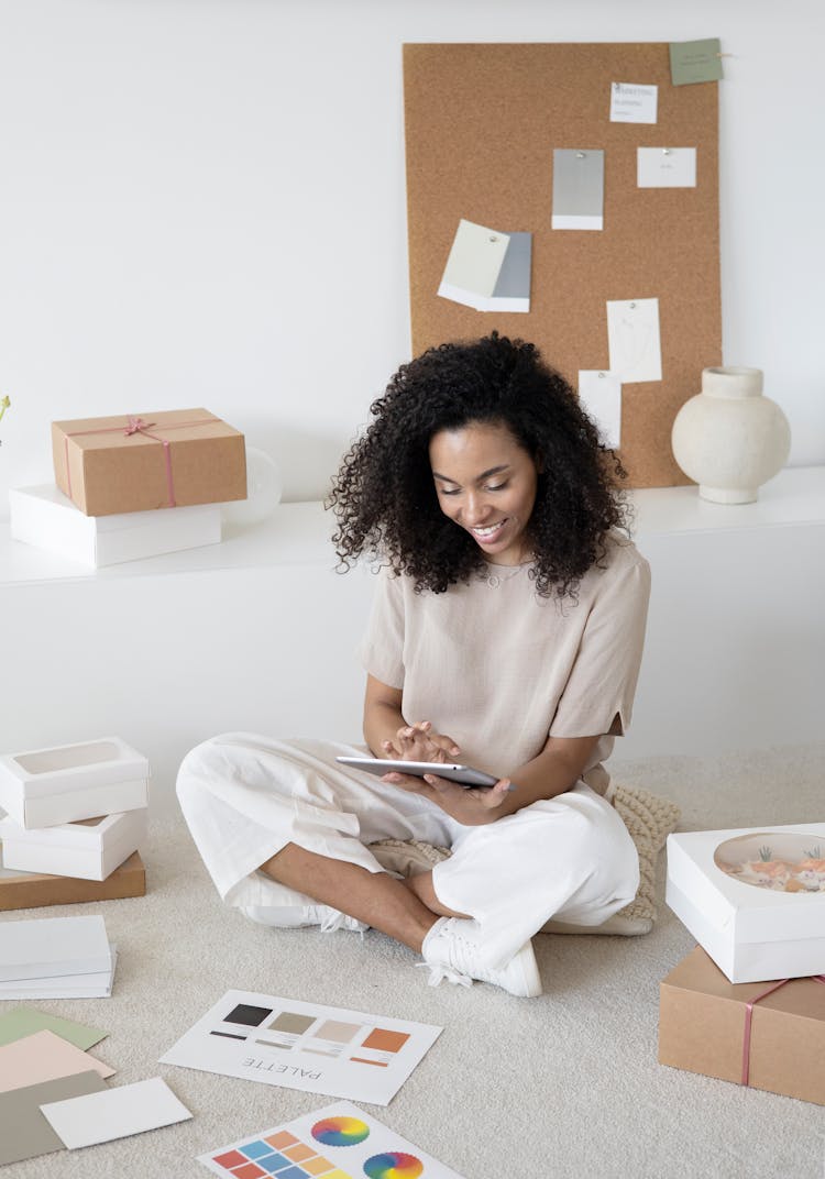 A Woman Sitting On A Floor Holding A Tablet