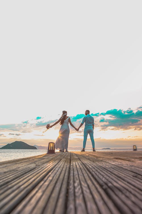 Low-Angle Shot of a Groom and a Bride Holding Hands · Free Stock Photo