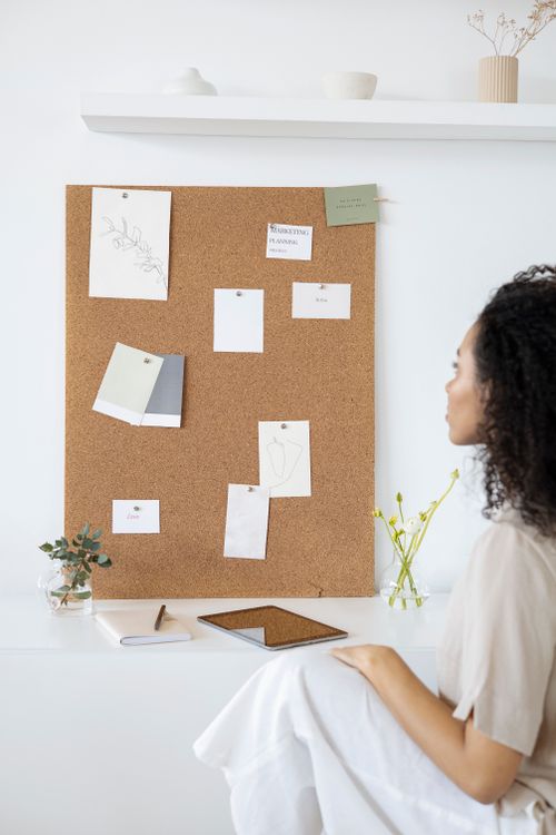 Free Woman looking at a mood board in a creative workspace setting, ideal for design inspiration. Stock Photo