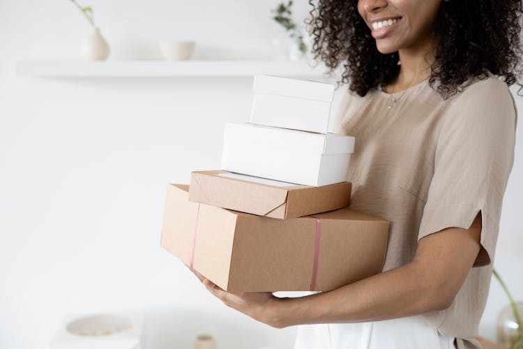 A Woman Smiling While Carrying Boxes