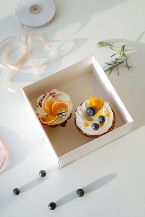 Free Delicious gourmet cupcakes with fresh fruit toppings neatly placed in a stylish gift box, perfect for special occasions. Stock Photo