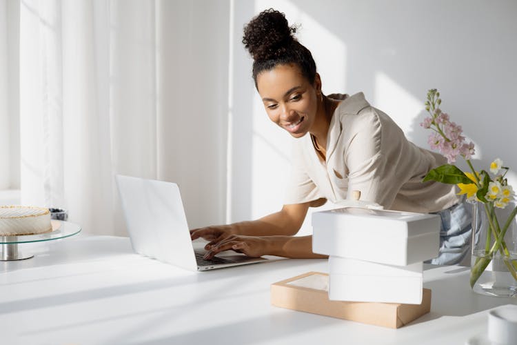 A Woman Typing While Looking At Boxes