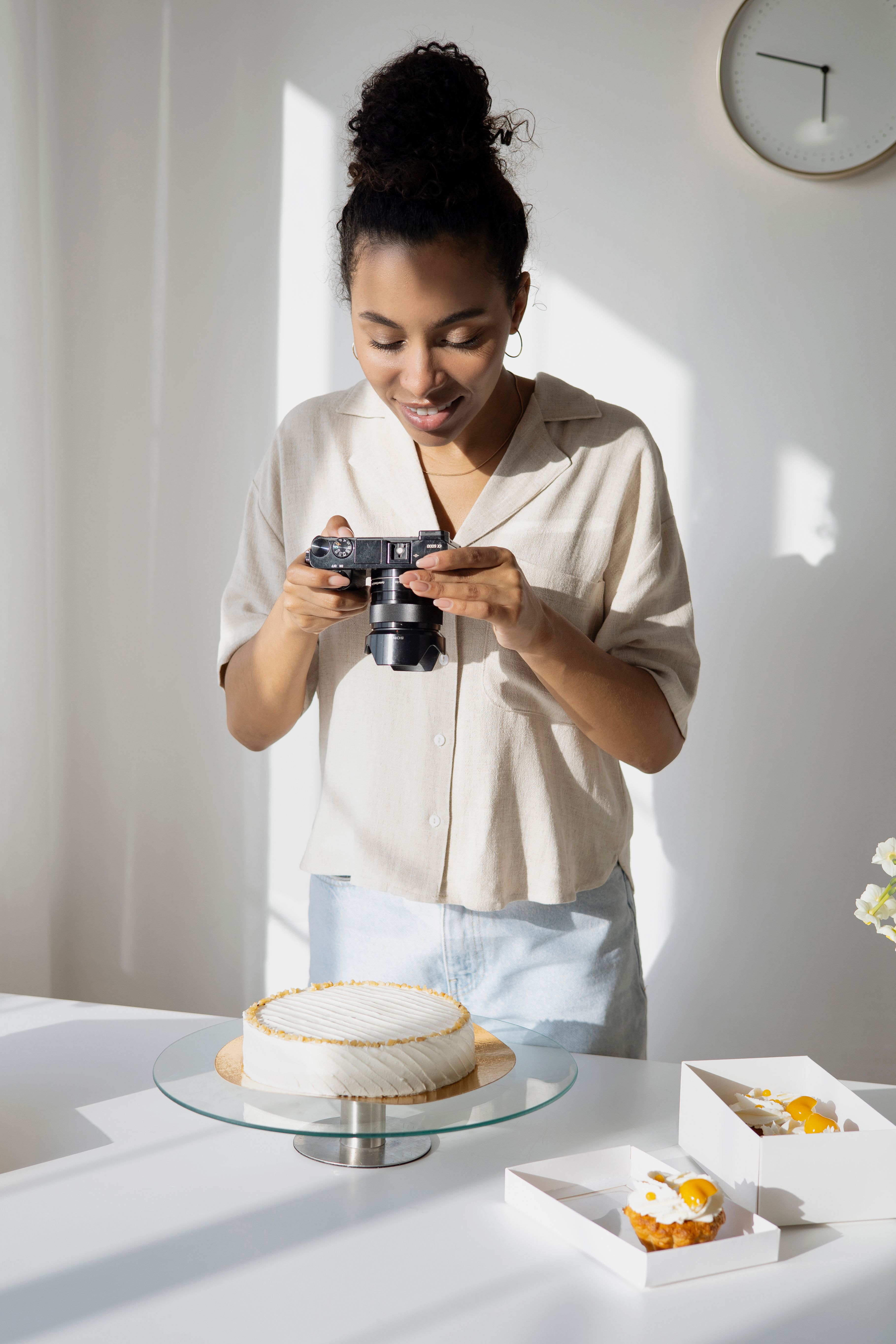 A woman captures a cake photo in a bright, minimalist kitchen setting