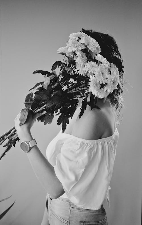 Grayscale Photo of a Woman Covering Her Face with Flowers