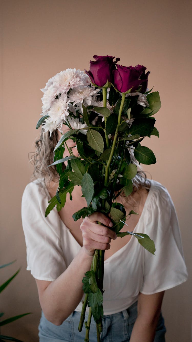 Woman Covering Her Face With Bouquet Of Flowers