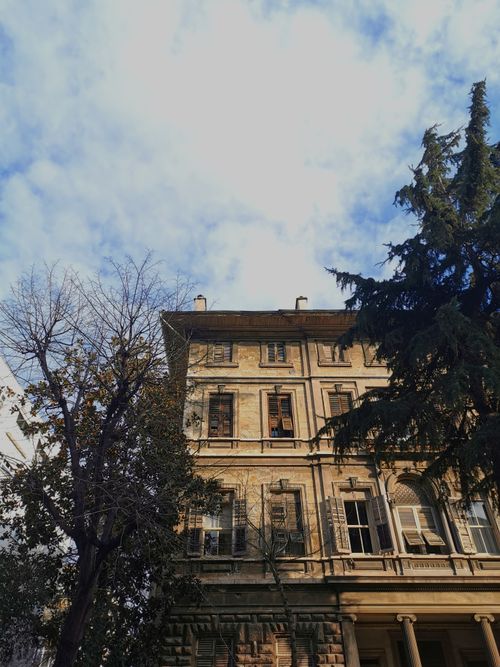 Free A low-angle view of a classic building in Kadıköy, Istanbul, framed by trees and a vibrant blue sky. Stock Photo
