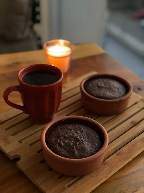 Red Ceramic Mug and Brown Puddings on Wooden Board