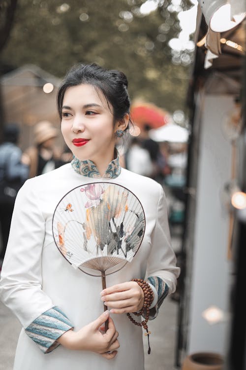 Selective Focus Photo of a Woman Holding a Hand Fan 