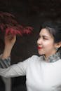 Close-Up Photo of a Woman Looking at Red Leaves
