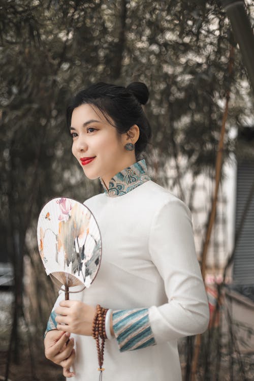 Woman in a Traditional Clothing Holding a White Hand Fan
