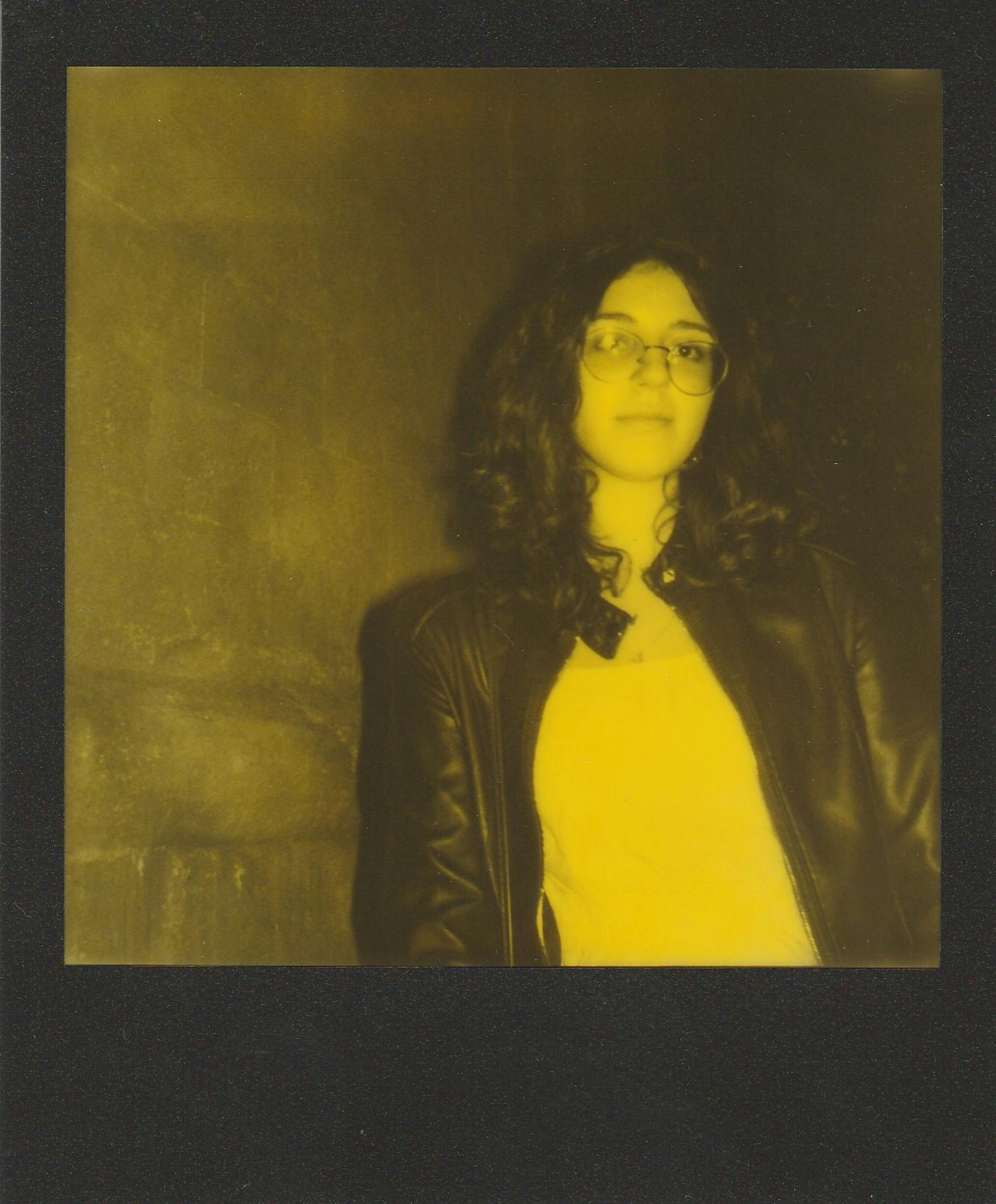 Stylish woman wearing glasses and leather jacket captured in vintage polaroid style.