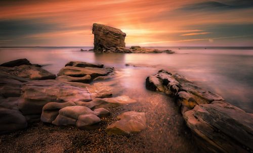 Free Beautiful sunset over a rocky beach, showcasing stunning colors and natural formations. Stock Photo