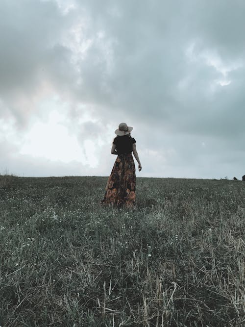 Unrecognizable woman walking on grassy meadow