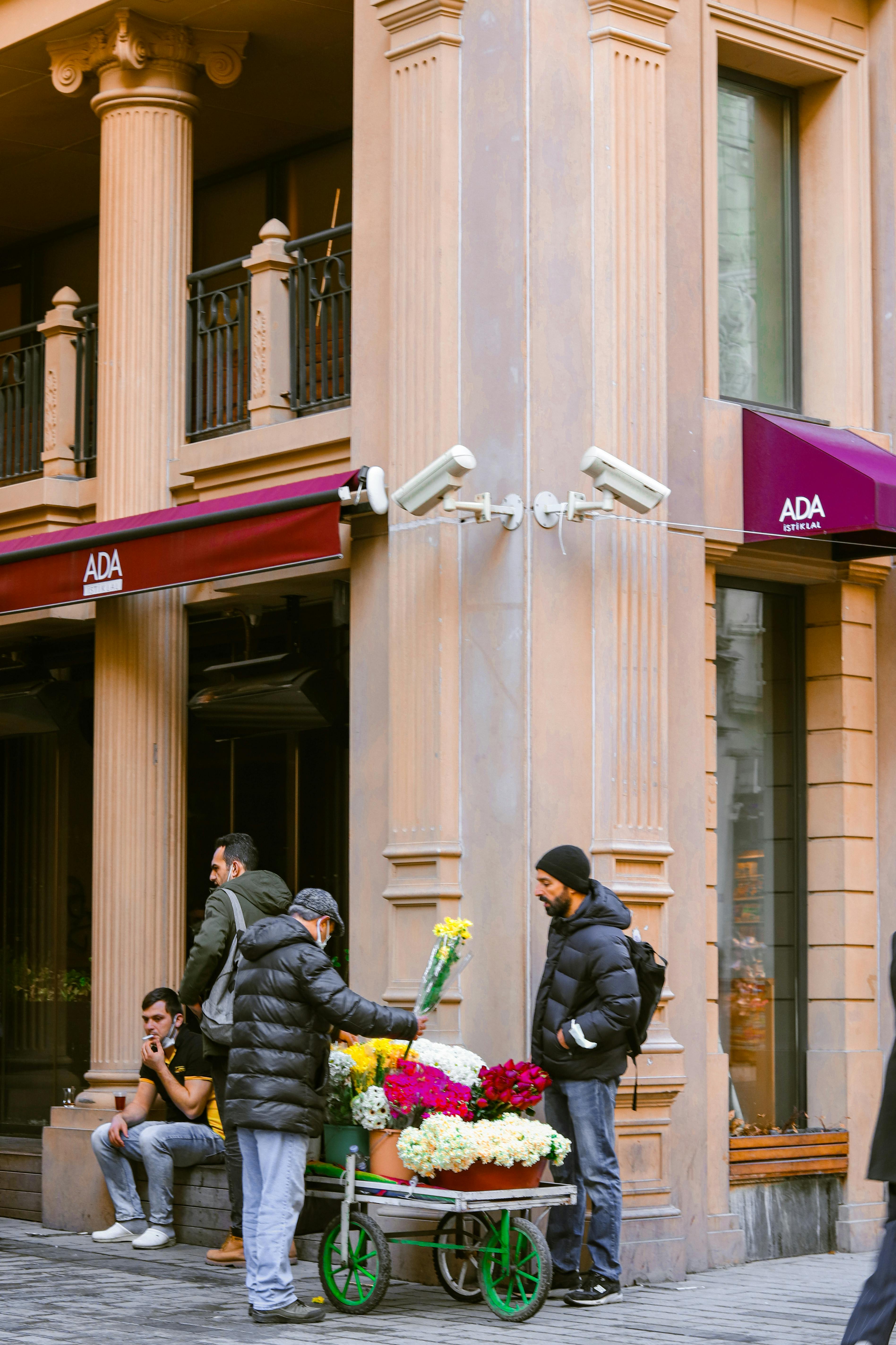 Free Flower vendor with colorful bouquets on city street corner by classic architecture. Stock Photo