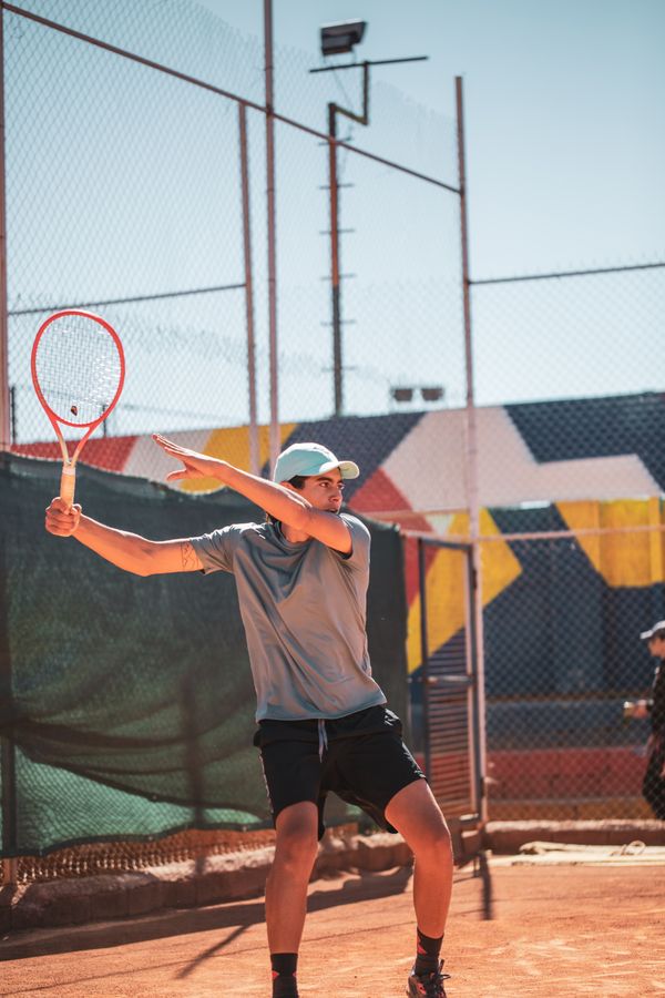 Player swinging a racket on an outdoor clay court