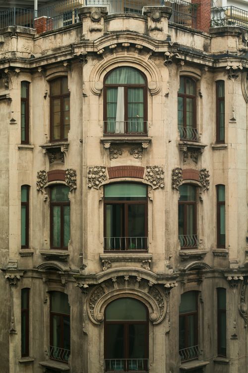 Free Exterior of aged classic residential house with balconies and windows with metal fence and decorative elements located on street of town Stock Photo