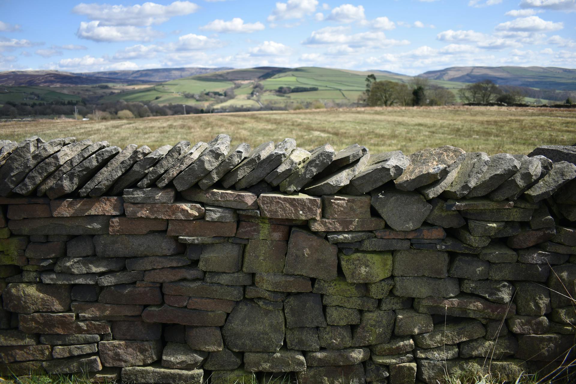 Beautiful English countryside landscape with traditional dry stone wall and rolling hills.