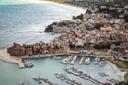 A picturesque aerial shot of a coastal town in Sicily, showcasing the marina and historic architecture.