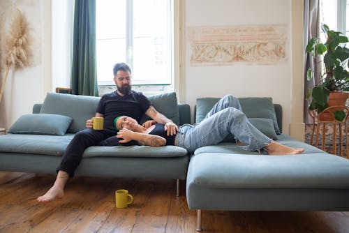 Free Man Sitting on a Couch with Woman Lying on his Lap Stock Photo