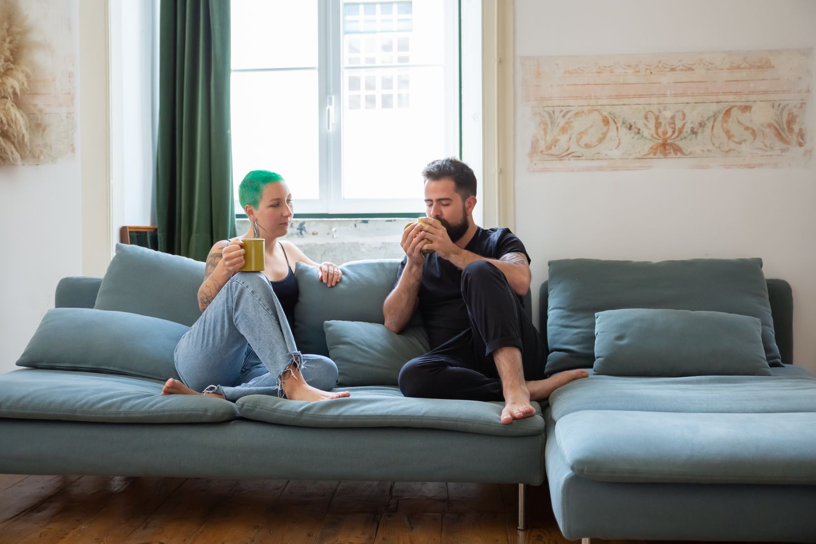Two people sitting on a sofa with mugs