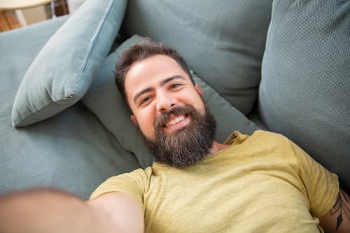 Free A Man in Yellow Crew Neck T-shirt Lying on Gray Sofa Stock Photo