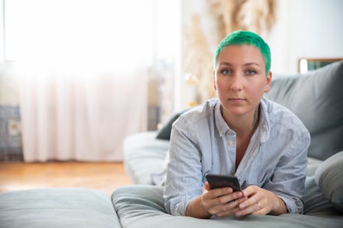 A Woman with Green Hair Holding a Black Smartphone