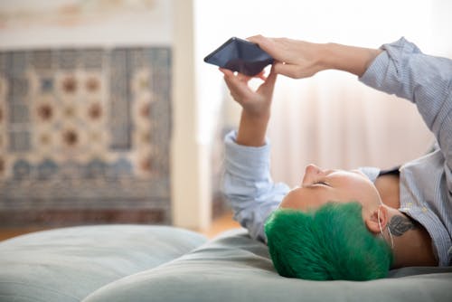 Free A Person with Green Hair Lying on Bed Stock Photo