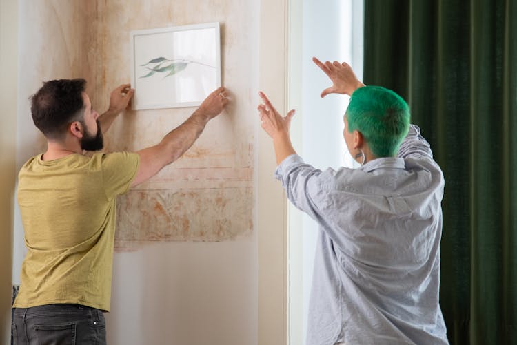 A Couple Hanging A Wall Frame