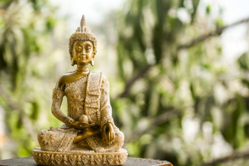 Free Close-up of a serene golden Buddha statue against a blurred natural background. Stock Photo