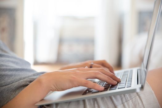 Close-up of hands typing on a laptop indoors, depicting remote work lifestyle.
