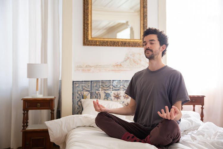 Man In Black Crew Neck Doing Meditation In Bed